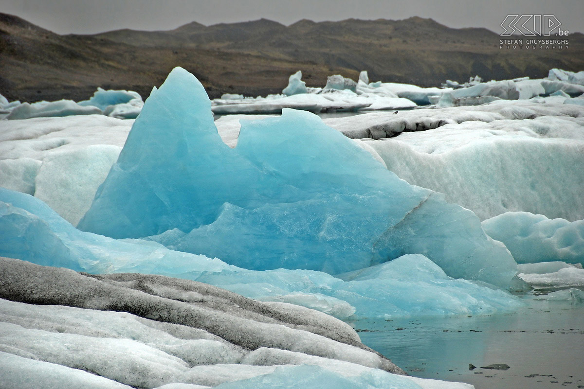 Jökulsárlon Het oudere gletsjerijs heeft vaak een schitterende blauwe kleur, zelfs op een grijze koude dag. Dit komt omdat alle luchtmoleculen eruit geperst zijn en de watermoleculen alle kleuren licht met uitzondering van blauw absorberen. Stefan Cruysberghs